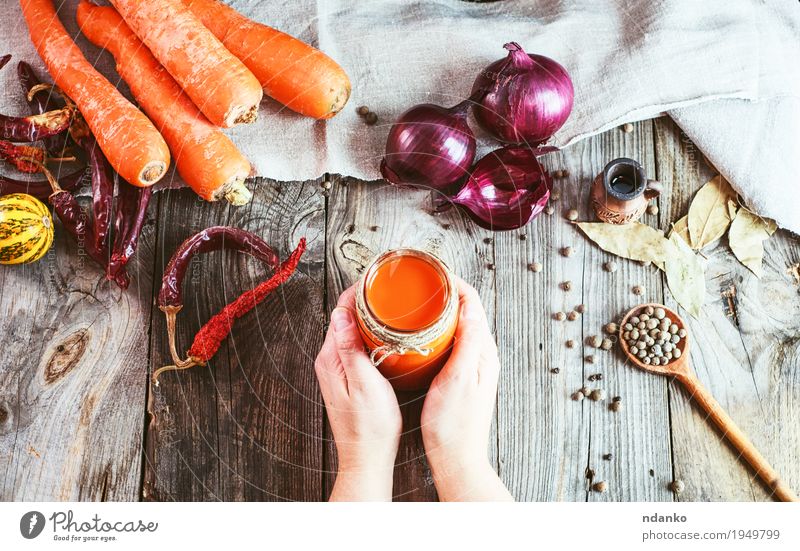 Weibliche Hände, die ein Glas mit einem Glas frischem Karottensaft halten Gemüse Kräuter & Gewürze Ernährung Essen trinken Saft Flasche Löffel Körper Haut Tisch