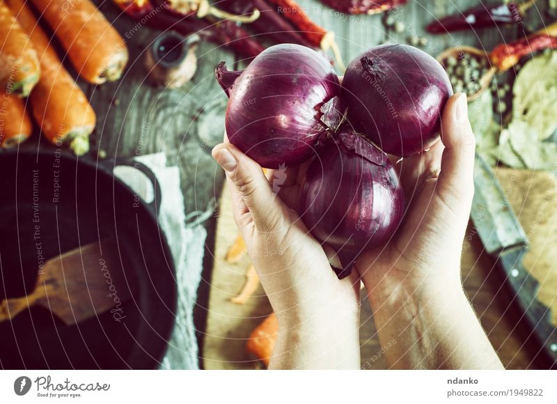 weibliche Hände halten drei rote Zwiebeln Gemüse Kräuter & Gewürze Ernährung Vegetarische Ernährung Pfanne Messer Löffel Tisch feminin Hand Finger 1 Mensch