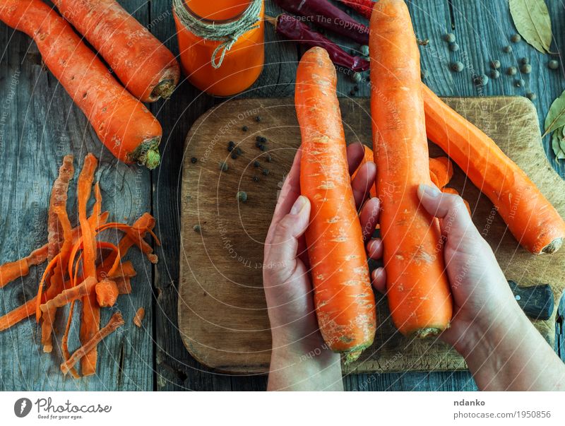 Zwei große reife Karotten liegen in den weiblichen Händen Gemüse Ernährung Vegetarische Ernährung Diät Getränk Saft Flasche Körper Gesunde Ernährung Tisch Frau