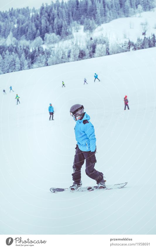 Junge, der einen Snowboard den Abhang hinunter reitet Freude Ferien & Urlaub & Reisen Winter Schnee Winterurlaub Berge u. Gebirge Sport Natur Landschaft Hügel