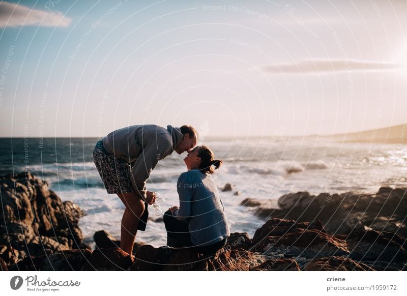 Kaukasische Paare des jungen Erwachsenen, die auf Klippe in Ozean küssen Lifestyle Freude Ferien & Urlaub & Reisen Tourismus Ausflug Abenteuer Strand Meer