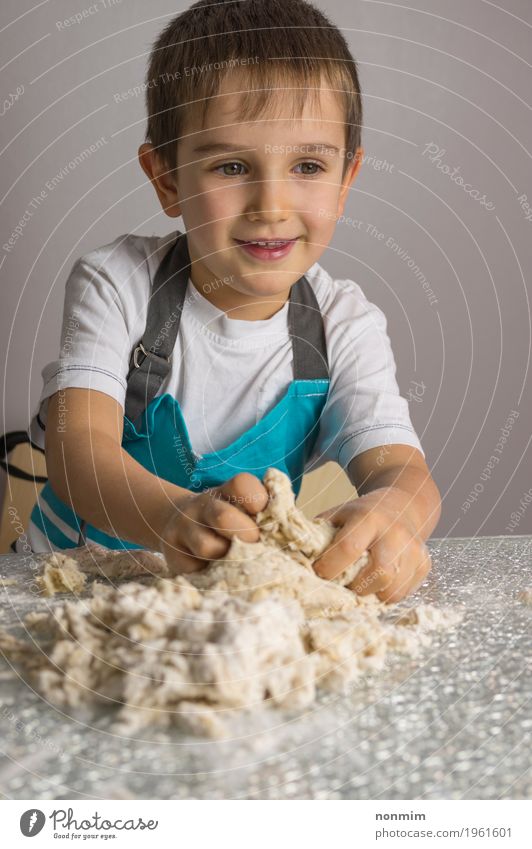 Kleiner Junge knetet rohen Pizzateig und -c $ lächeln Teigwaren Backwaren Brot Freude Spielen Küche Kind Lächeln machen blau reizvoll Schürze backen Bäcker