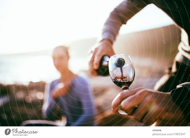 Füllendes Glas des Mannes mit Wein auf Datum am Strand im Sonnenuntergang Picknick Getränk Alkohol Flasche Lifestyle Freude Glück Sommer Flirten Mensch Frau
