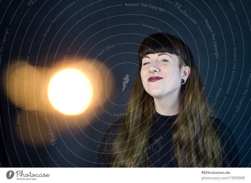 Carina - glückliche Frau vor einer schwarzen Wand mit Lichteffekt Lichterscheinung Junge Frau 18-30 Jahre Gesicht außergewöhnlich Coolness brünett langhaarig