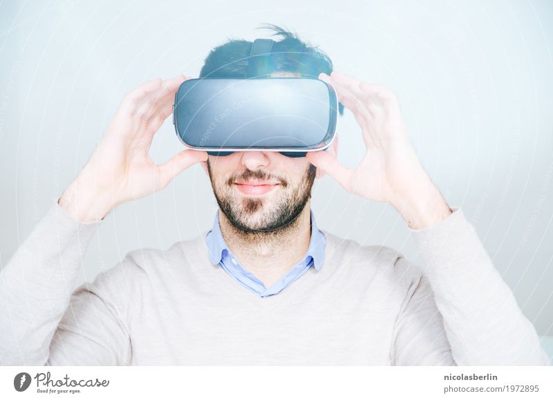 Junger Mann trägt VR-Brille und lächelt auf weißem Hintergrund virtuell Freude Lächeln virtuelle realität virtual reality simulator Spielen Computerspiel Erfolg