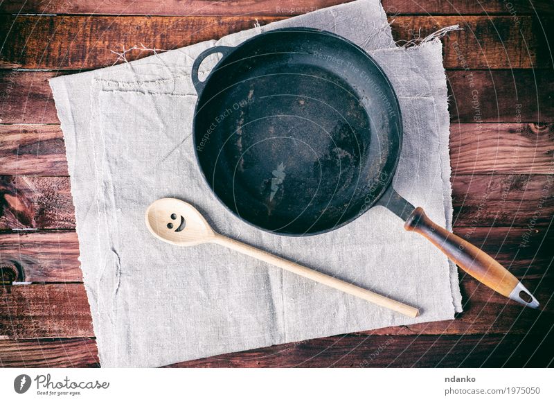 Gusseisenpfanne mit einem Spachtel auf einer grauen Textilserviette Geschirr Pfanne Löffel Design Tisch Küche Restaurant Werkzeug Stoff Holz Metall oben
