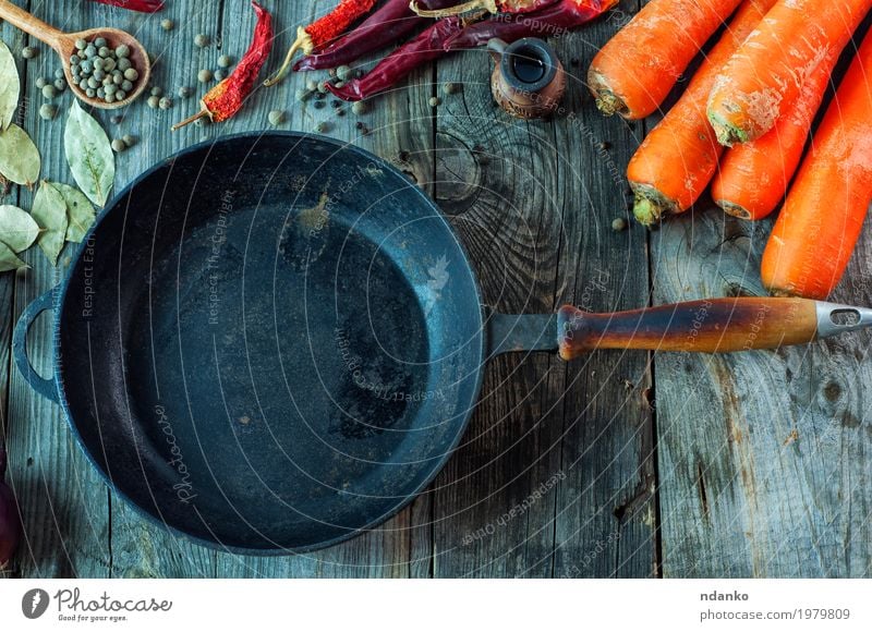 Schwarze leere Gusseisenbratpfanne unter Gemüse Lebensmittel Kräuter & Gewürze Ernährung Vegetarische Ernährung Pfanne Löffel Tisch Küche Holz Metall Essen