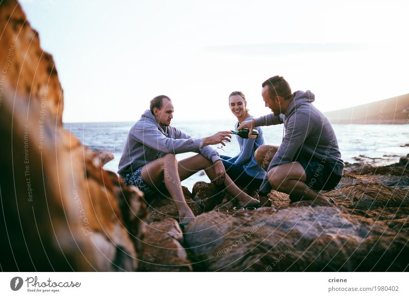 Junge erwachsene Freunde, die Picknick mit Wein durch Ozean haben trinken Alkohol Flasche Lifestyle Ferien & Urlaub & Reisen Abenteuer Strand Meer