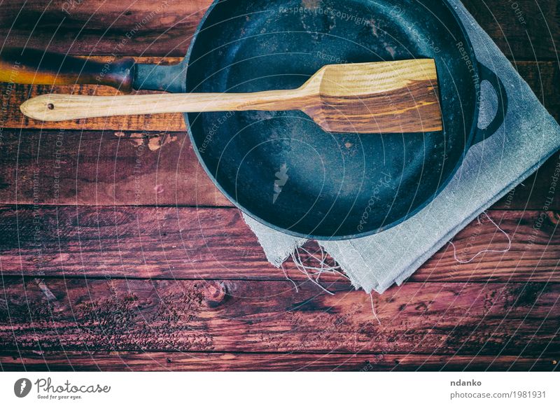 Leere Bratpfanne auf einer braunen Holzoberfläche Geschirr Pfanne Tisch Küche Werkzeug Stoff Metall oben Sauberkeit schwarz Tischwäsche Spachtel Kopie Aussicht