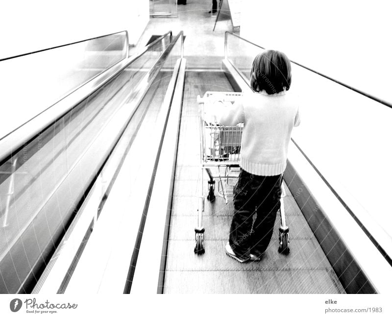 Einkaufsequenz 1 Rolltreppe Einkaufswagen Kind schieben Supermarkt Mensch Konsum Schwarzweißfoto