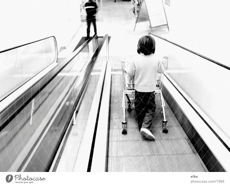 Einkaufsequenz Rolltreppe Einkaufswagen Kind kaufen schieben Supermarkt Mensch Schwarzweißfoto