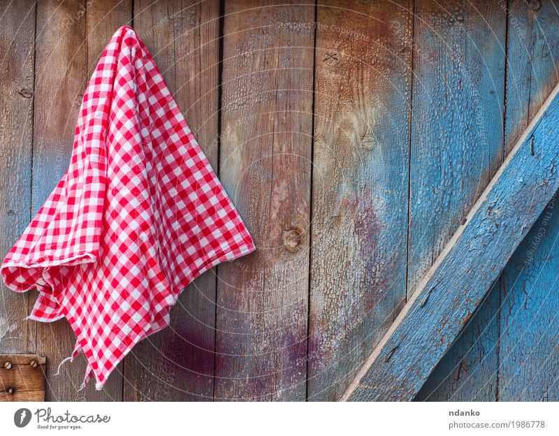 Roter Stoff in einer Zelle, die an einer hölzernen gebrochenen Wand hängt Design Küche Holz alt blau rot weiß Oberfläche Tischwäsche Pfeife Serviette