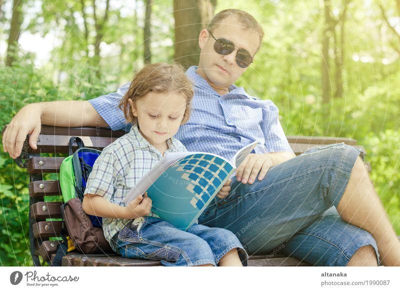 Vater und Sohn, die am Park auf Bank zur Tageszeit spielen. Lifestyle Freude Leben Erholung Freizeit & Hobby Spielen lesen Ferien & Urlaub & Reisen Freiheit