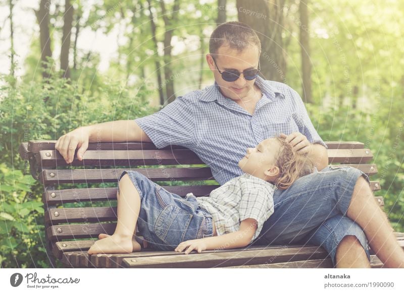 Vater und Sohn, die am Park auf Bank zur Tageszeit spielen. Lifestyle Freude Glück Leben Freizeit & Hobby Spielen Ferien & Urlaub & Reisen Freiheit Sommer Sonne
