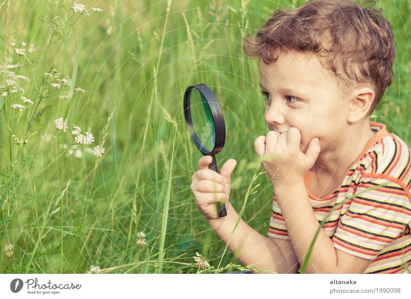 Glücklicher kleiner Junge erforscht die Natur mit Lupe am Tag Lifestyle Freude Gesicht Spielen Sommer Garten Wissenschaften Kind Schule Mensch Kindheit Hand