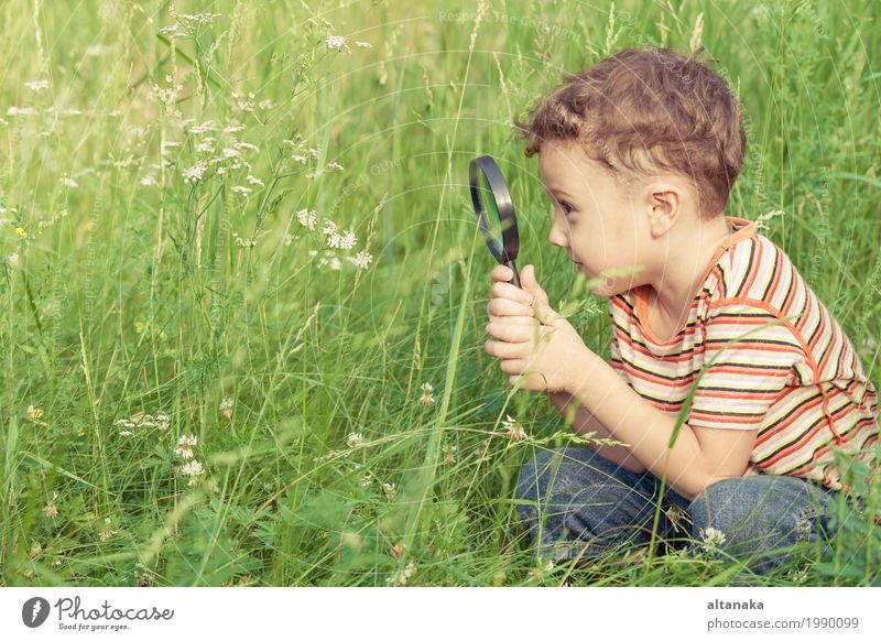 Glücklicher kleiner Junge erforscht die Natur mit Lupe am Tag Lifestyle Freude Gesicht Spielen Sommer Garten Wissenschaften Kind Schule Mensch Kindheit Hand