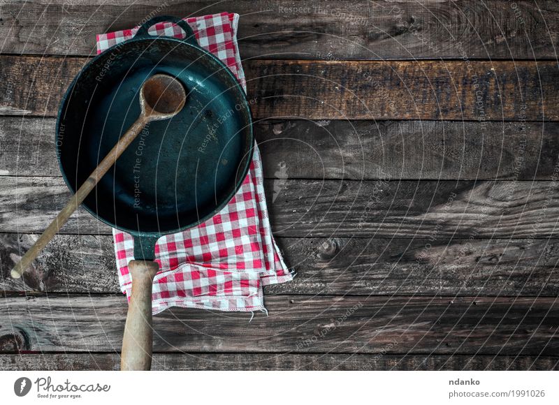 Schwarze Bratpfanne mit einem Löffel auf einer braunen Holzoberfläche Geschirr Pfanne Tisch Küche Restaurant Werkzeug Stoff Metall alt oben Sauberkeit schwarz
