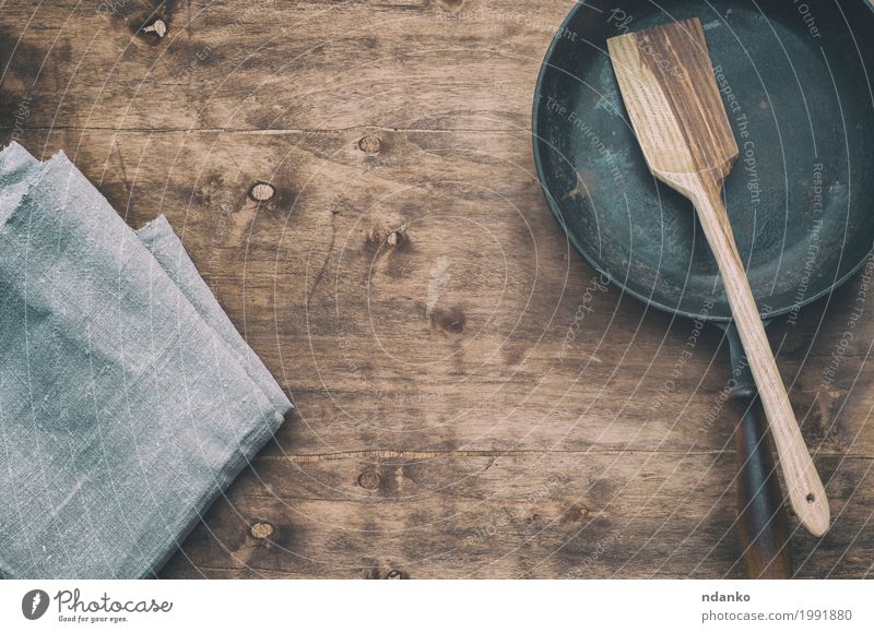 Schwarze Bratpfanne mit einer Küchenspachtel, braune Oberfläche Geschirr Pfanne Tisch Restaurant Werkzeug Stoff Holz Metall alt oben Sauberkeit schwarz