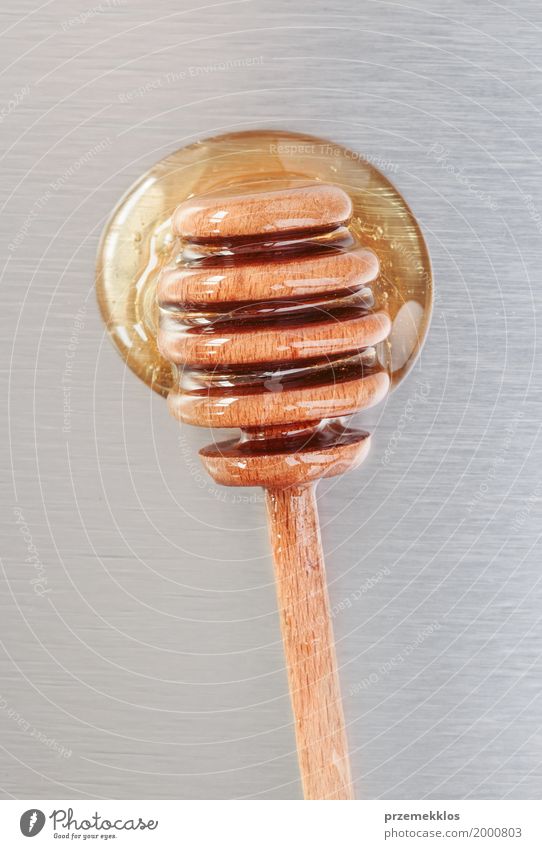 Nahaufnahme des Honigschöpflöffels auf einer Metalloberfläche Lebensmittel Süßwaren Ernährung Bioprodukte Diät Holz Tropfen frisch Gesundheit natürlich oben