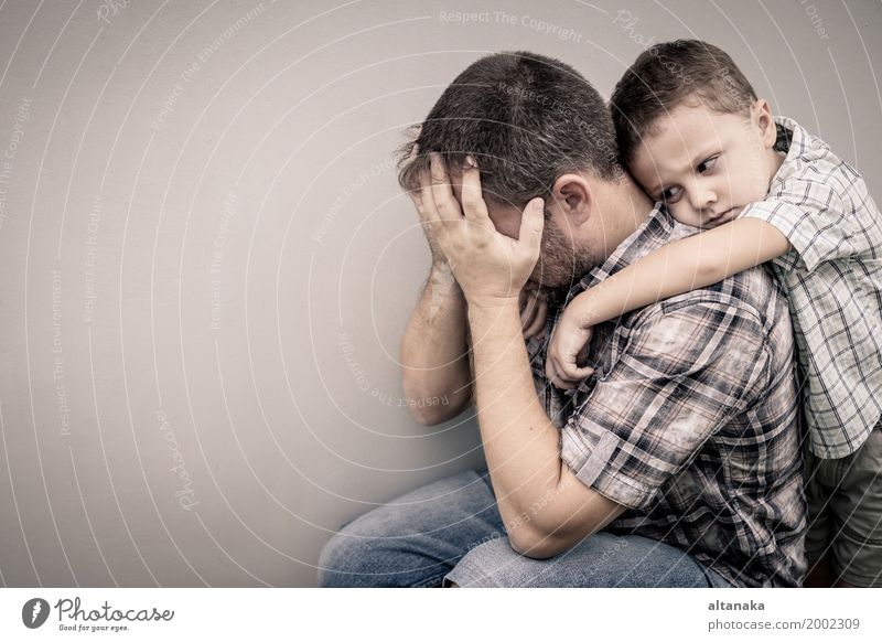 trauriger Sohn, der seinen Vater tagsüber nahe der Mauer umarmt Gesicht Kind Junge Mann Erwachsene Eltern Familie & Verwandtschaft Kindheit Traurigkeit Umarmen