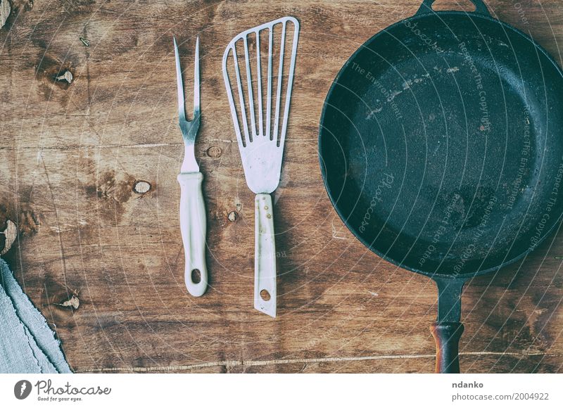Leere schwarze Gusseisenbratpfanne mit Weinlesekücheneinzelteilen Geschirr Pfanne Tisch Küche Restaurant Werkzeug Holz Metall oben Sauberkeit braun Spachtel