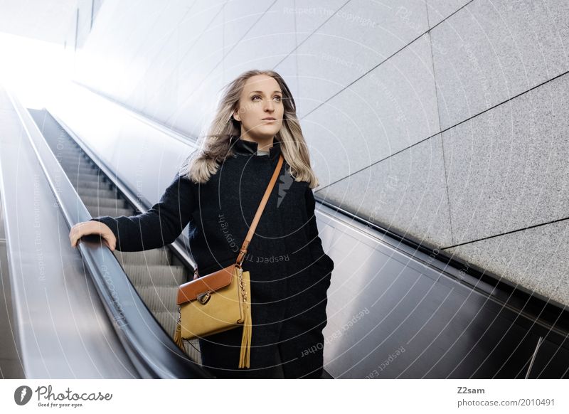 Frau auf Rolltreppe Lifestyle elegant Stil Erwachsene 18-30 Jahre Jugendliche Stadt Mode Mantel Tasche blond langhaarig Denken fahren Lächeln träumen Glück