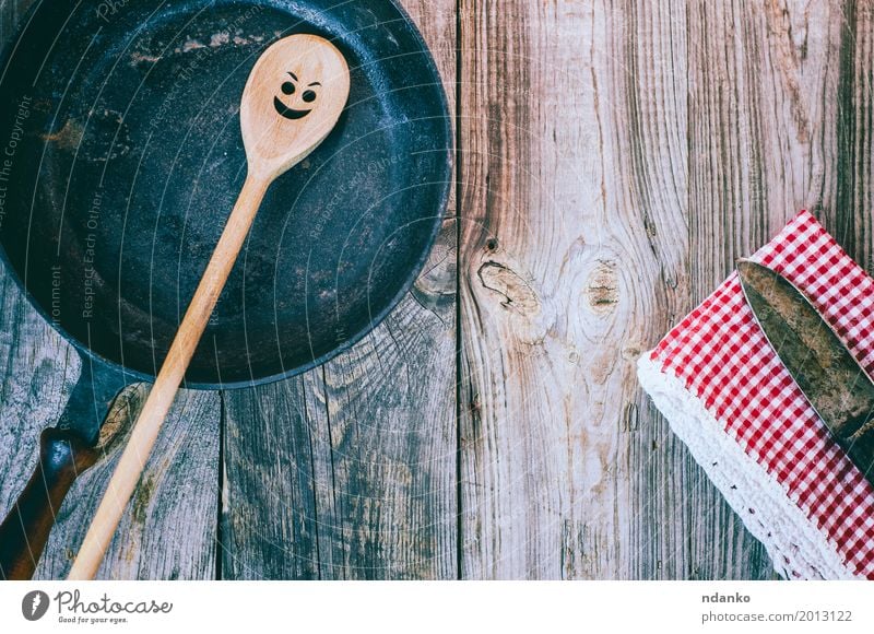 Schwarze Bratpfanne der Weinlese mit einem hölzernen Löffel Geschirr Pfanne Tisch Küche Restaurant Stoff Holz Metall alt oben Sauberkeit rot schwarz Gefühle