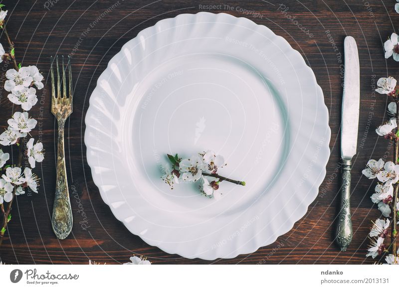 Weiße Platte mit einer Gabel und Messer auf einer braunen Holzoberfläche Mittagessen Abendessen Teller Besteck Tisch Küche Restaurant Blume Platz Metall alt
