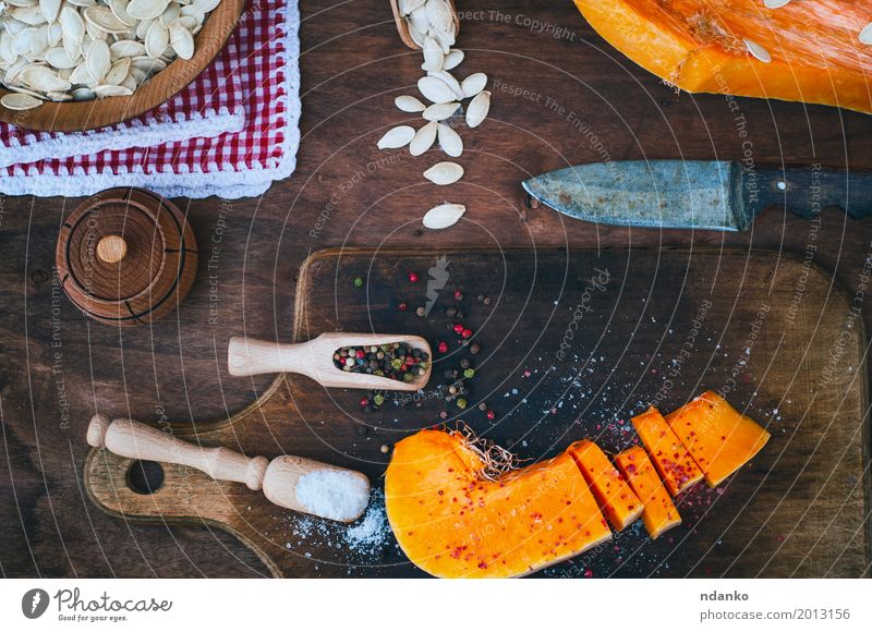 Stück frischer Kürbis mit Salz und Pfeffer Lebensmittel Gemüse Kräuter & Gewürze Ernährung Messer Löffel Holz Essen oben braun orange weiß Paprika Koch Zutaten