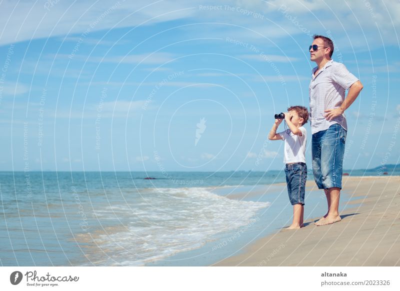 Vater und Sohn mit Fernglas stehen am Strand zur Tageszeit. Konzept der freundlichen Familie. Lifestyle Freude Leben Erholung Freizeit & Hobby Spielen