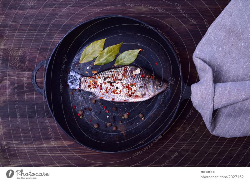 Crucian Karpfen in Gewürzen auf einer schwarzen Gusseisen Bratpfanne Lebensmittel Fisch Kräuter & Gewürze Ernährung Pfanne Tisch Küche Natur Blatt Holz Diät