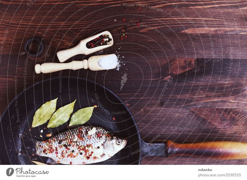 Fischkarpfen mit Gewürzen in einer schwarzen Gusseisenpfanne Lebensmittel Kräuter & Gewürze Pfanne Tisch Küche Natur Blatt Holz Diät Essen frisch natürlich oben