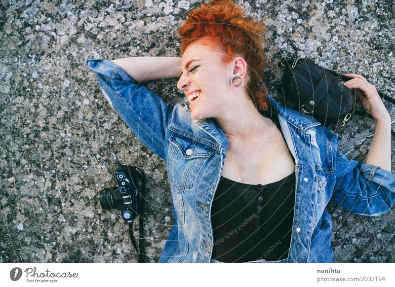 Junge Rothaarigefrau, die auf Boden mit ihrer Tasche und ihrer Kamera liegt Lifestyle elegant Stil Leben Wohlgefühl Fotografie Ferien & Urlaub & Reisen