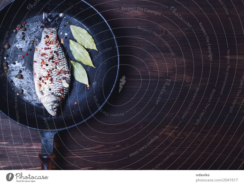 Fisch in Gewürzen auf einer schwarzen Gusseisenpfanne Kräuter & Gewürze Ernährung Pfanne Tisch Küche Holz frisch lecker natürlich oben braun Kruzianer Paprika