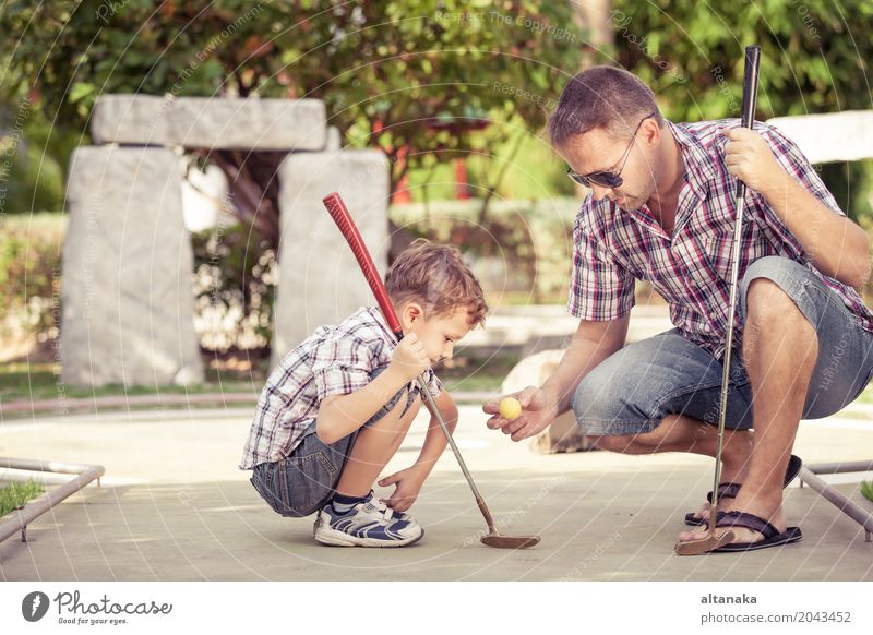 Netter junger Mann, der seinen Sohn unterrichtet, Minigolf zu spielen Lifestyle Freude Glück Erholung Freizeit & Hobby Spielen Ferien & Urlaub & Reisen Freiheit