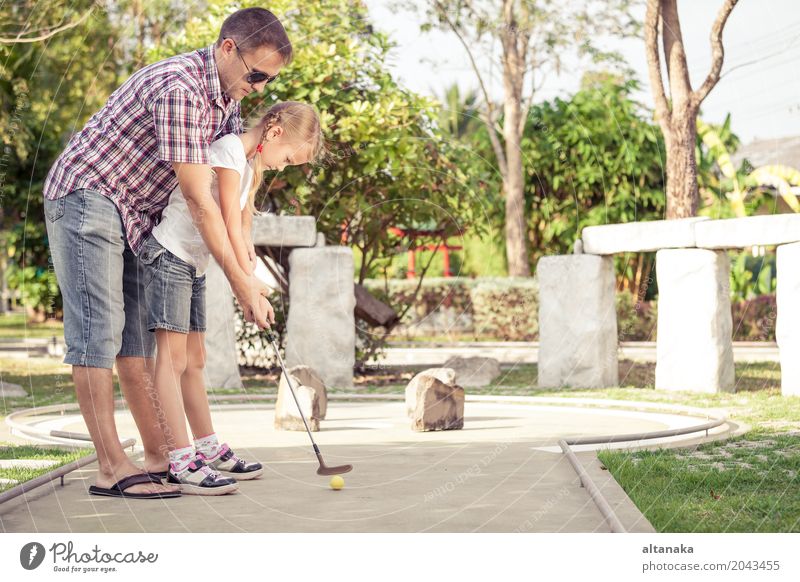 Netter junger Mann, der seine Tochter unterrichtet, Minigolf zu spielen Lifestyle Freude Glück Erholung Freizeit & Hobby Spielen Ferien & Urlaub & Reisen