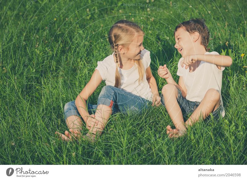 Zwei glückliche Kinder, die nahe einem Baum auf dem Gras spielen Lifestyle Freude Glück schön Gesicht Freizeit & Hobby Spielen Ferien & Urlaub & Reisen Freiheit