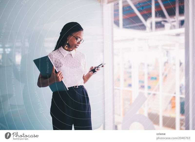 Junge afroamerikanische Geschäftsfrau nutzt Smartphone im Büro Lifestyle lesen Erfolg Arbeit & Erwerbstätigkeit Kapitalwirtschaft Business Karriere PDA Notebook