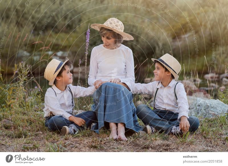Großmutter mit ihren Enkelkindern, die auf dem Gebiet sitzen Lifestyle Freude Garten Mensch maskulin feminin Kind Kleinkind Junge Geschwister Bruder Großeltern