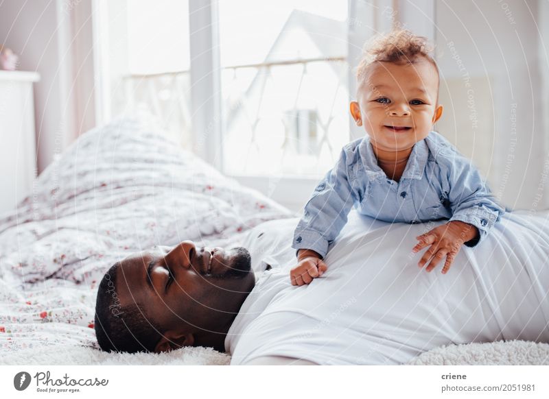 Junger afroamerikanischer Vater und Kleinkind kuscheln zusammen. Lifestyle Freude Glück Schlafzimmer Mensch maskulin Baby Junger Mann Jugendliche Erwachsene