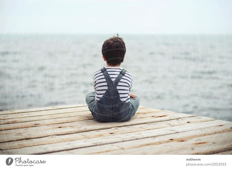 Nachdenkliches Kind sitzt am Wasser. Ansicht von hinten Lifestyle Mensch Kleinkind Junge 1 3-8 Jahre Kindheit Fitness Ferien & Urlaub & Reisen träumen
