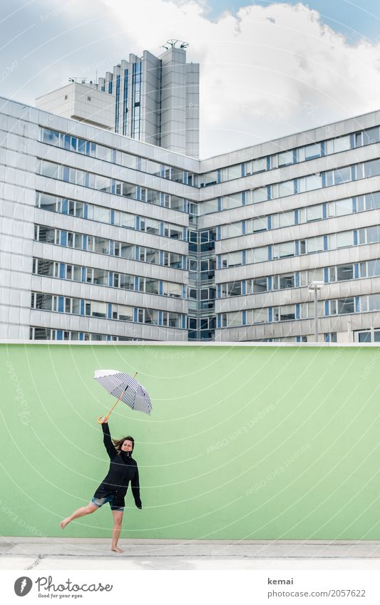 Frau mit Regenschirm vor grüner Wand, im Hintergrund Hochhäuser Lifestyle Leben Wohlgefühl Zufriedenheit Freizeit & Hobby Spielen Ausflug Abenteuer Freiheit