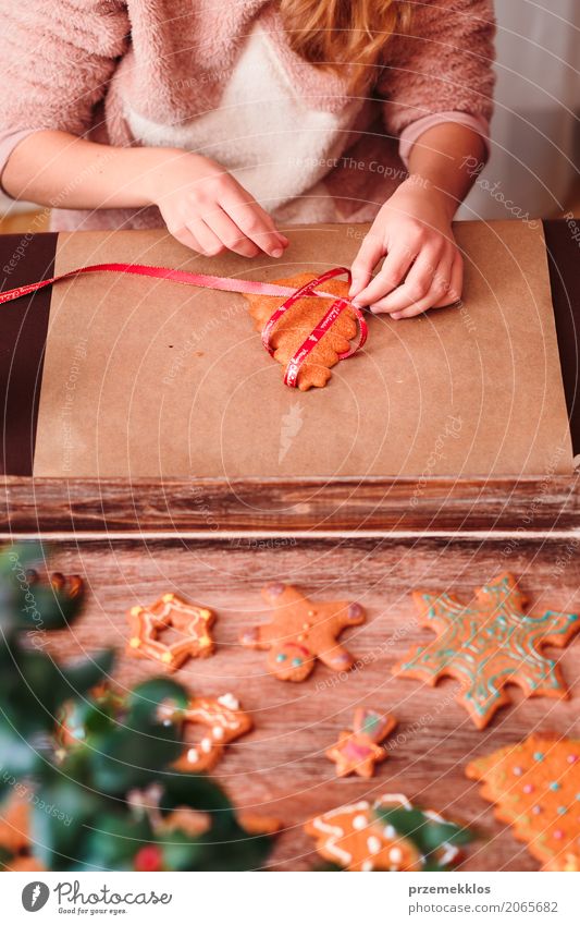 Mädchen, das gebackene Weihnachtslebkuchenplätzchen mit Band bindet Lifestyle Dekoration & Verzierung Tisch Feste & Feiern Weihnachten & Advent Handwerk Mensch