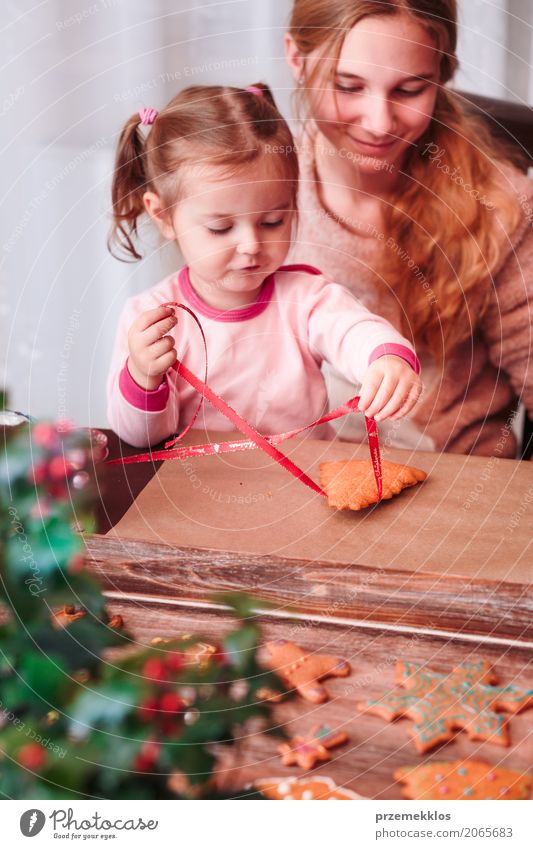 Mädchen, die gebackene Weihnachtslebkuchenplätzchen mit Band binden Lifestyle Dekoration & Verzierung Feste & Feiern Kind Handwerk Mensch