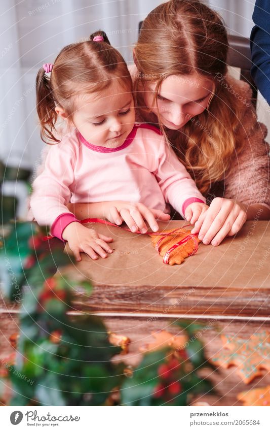 Mädchen, die gebackene Weihnachtslebkuchenplätzchen mit Band binden Lifestyle Dekoration & Verzierung Tisch Feste & Feiern Weihnachten & Advent Kind Mensch Frau