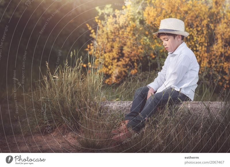 Nachdenklicher kleiner Junge auf einem Feld sitzend Lifestyle Mensch maskulin Kind Kleinkind Kindheit 1 3-8 Jahre Natur Frühling Sommer Herbst Garten Wald Hut