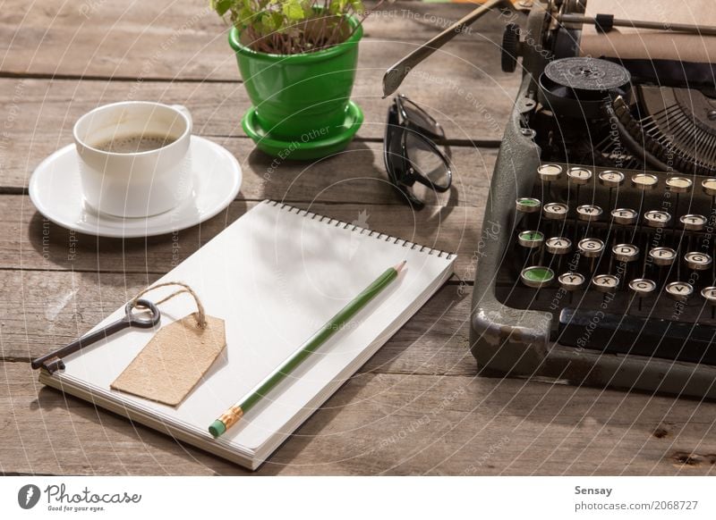 Vintage Schreibmaschine auf dem alten Schreibtisch aus Holz Kaffee Tee Topf Tisch Arbeitsplatz Büro Zeitung Zeitschrift Buch Pflanze Papier schreiben retro grün