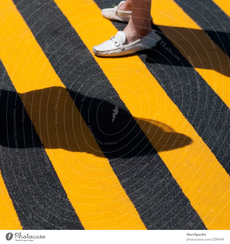 Schwarz-Gelb quo vadis? Fuß 1 Mensch Bodenmarkierung Schuhe gelb schwarz gestreift Warnfarbe Schatten körnig Farbfoto Außenaufnahme Licht Kontrast