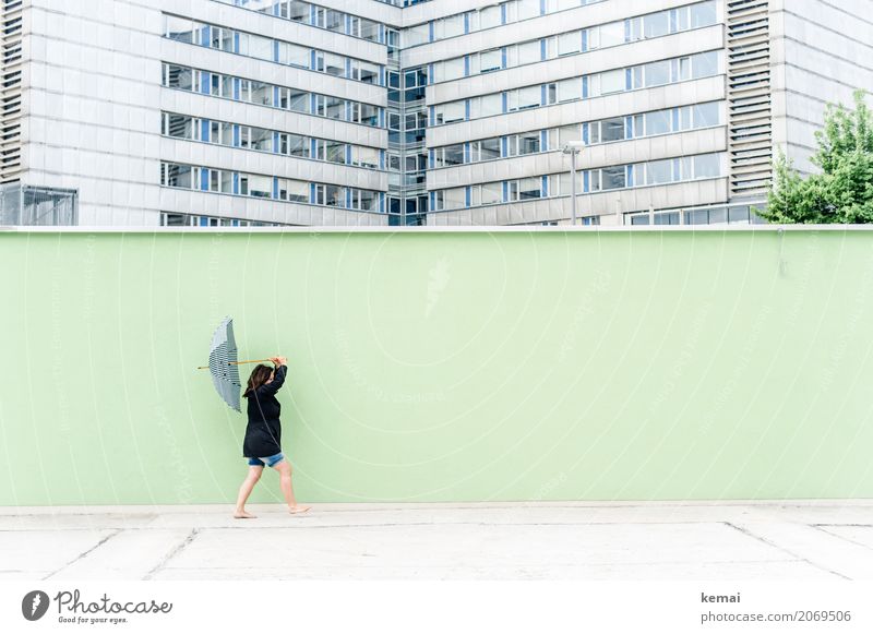 Frau mit Regenschirm vor grüner Wand, im Hintergrund Hochhäuser Lifestyle Leben harmonisch Freizeit & Hobby Ausflug Freiheit Mensch feminin Erwachsene 1