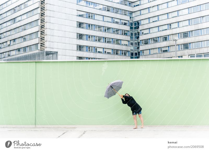 Frau mit Regenschirm vor grüner Wand, im Hintergrund Hochhäuser Freude Freizeit & Hobby Ferien & Urlaub & Reisen Ausflug Abenteuer Freiheit Städtereise Mensch